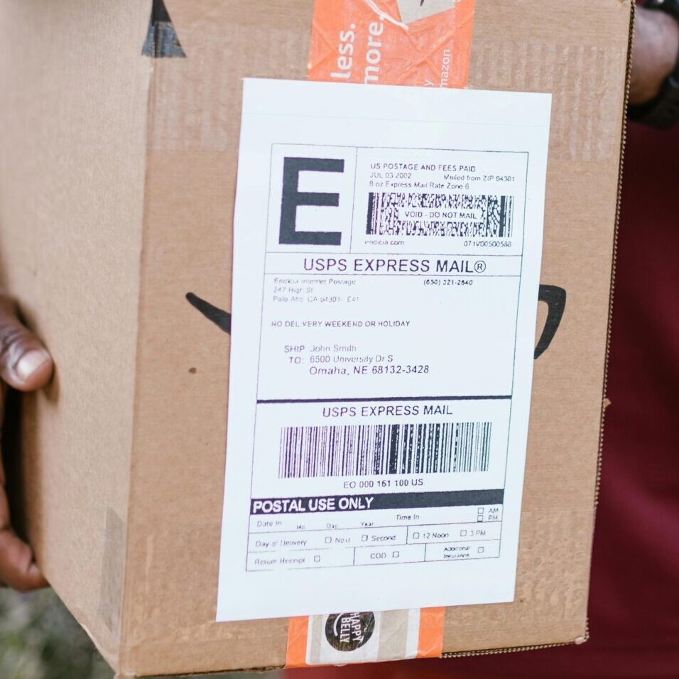 Close-up of a courier delivering a parcel with USPS express mail label outdoors.